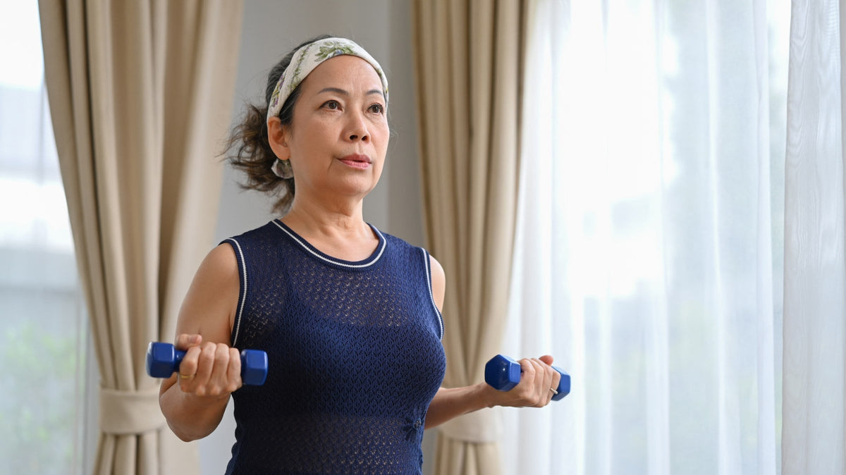 Middle-aged woman performing dumbbell curls at home as part of a strength-training routine