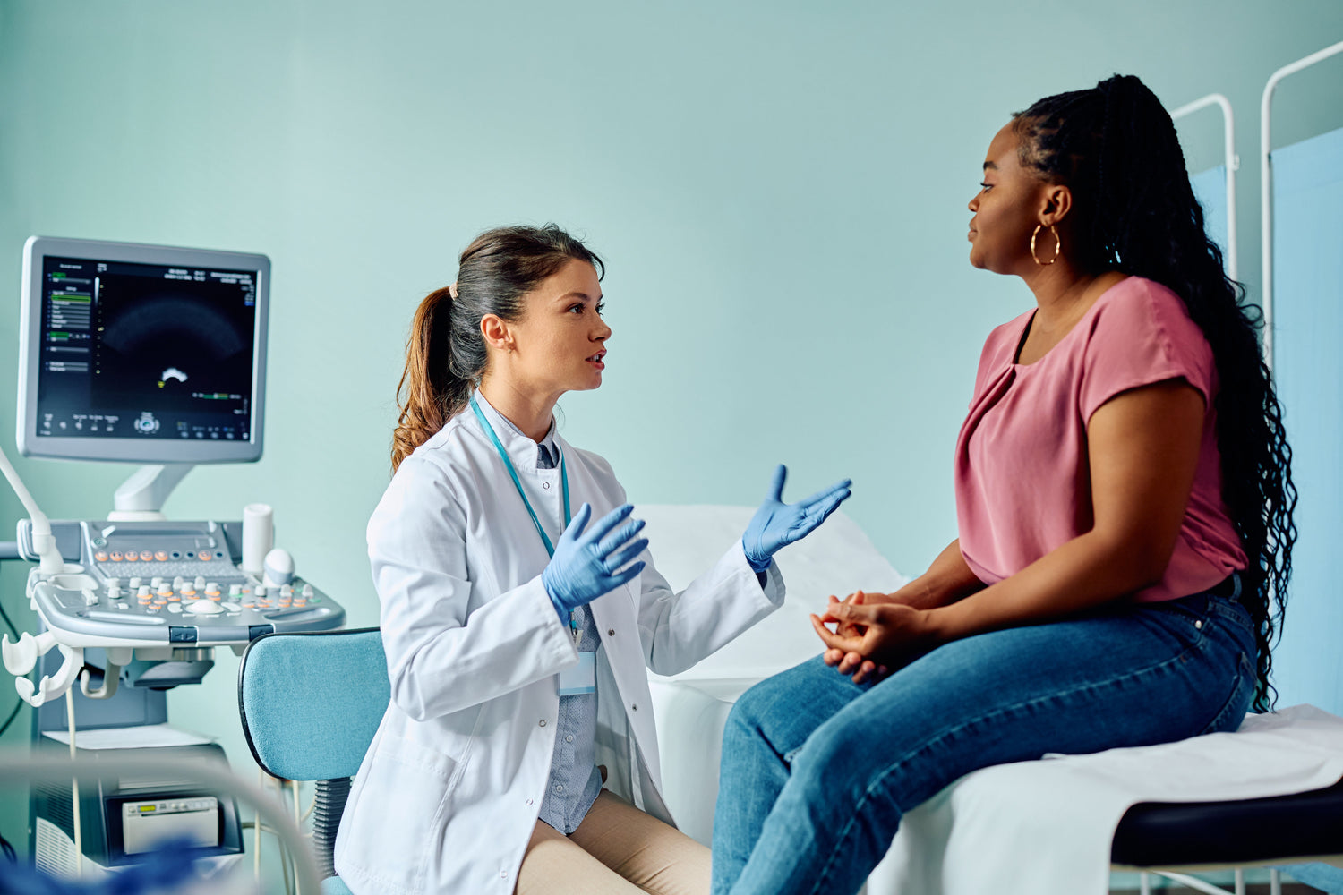 Doctor discussing PCOS/PMOS treatment options with a patient beside an ultrasound machine