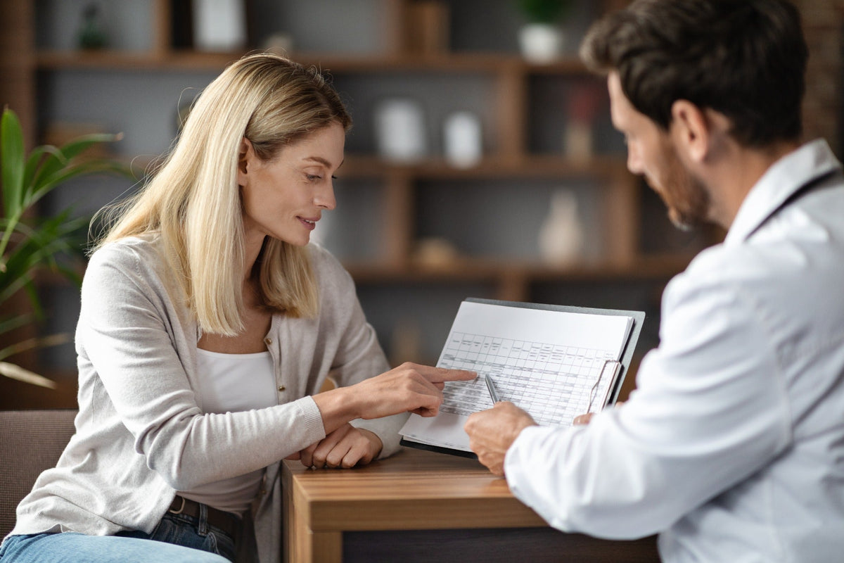Woman reviewing test results with her doctor during an office visit. Stock photo posed by models.